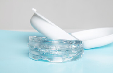 Anti snoring mouth guard made of reusable silicone shown on a white table or blue backdrop. The device is displayed from a side view or top view, clean and minimal, medical product style.