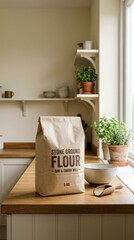 Brown paper bag of stone ground flour sits on a wooden kitchen countertop beside a bowl and wooden spoon, surrounded by potted plants and kitchenware, creating a cozy cooking atmosphere