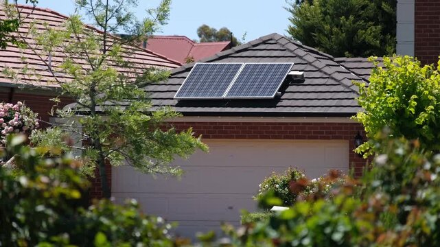 A suburban house in Australia featuring rooftop solar panels installed on a tiled garage roof. Concept of residential renewable energy, sustainable living, eco-friendly home upgrades, modern housing