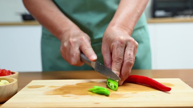 Slicing fresh chili for a healthy meal prep, showcasing cooking skills and kitchen tools with organic vegetables for a delicious and nutritious recipe.