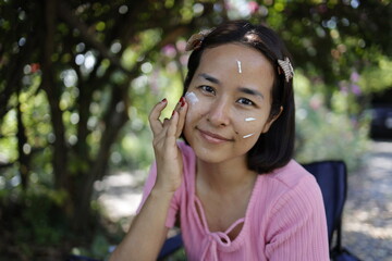 Woman applying skin care cream and sunscreen.
