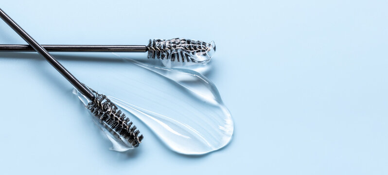 Close-up of transparent eyelash eyebrow gel serum, smooth and shiny texture stroke, blue background