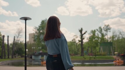 lady strolls near city pond, woman relaxes during sunset by water, individual leisurely walking along urban water during sunset, woman takes peaceful walk beside city water as day turns to night