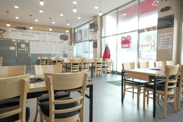 A restaurant with a lot of empty chairs and tables. The chairs are mostly wooden and black