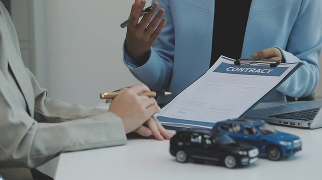 Man signing car insurance document or lease paper. Writing signature on contract or agreement. Buying or selling new or used vehicles. Car keys on table. Warranty or guarantee. Customer or salesman.