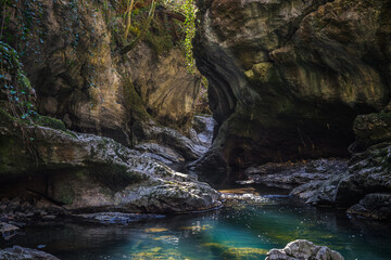 Sychryd Gorge with towering rock walls framing a turquoise stream of river Afon Sychryd flowing through scattered boulders in Vale of Neath, south Wales