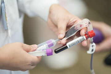 Selective focus hand of doctor blood draw patient into test tube while donating in...