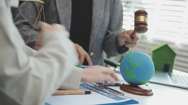 Professionals discussing sustainable and eco-friendly real estate projects, with a model house and wind turbine on the table.