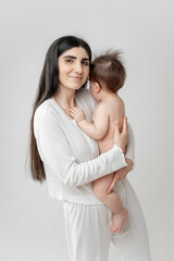 mother with a baby in a diaper on a white background, mother holding a small baby and kissing it, space and room for text