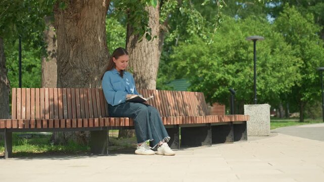 calm mindful reading, serene woman meditating outdoors, peaceful woman practicing mindfulness on shaded park bench, gentle summer sunlight accompanies woman calmly focusing on her breathing