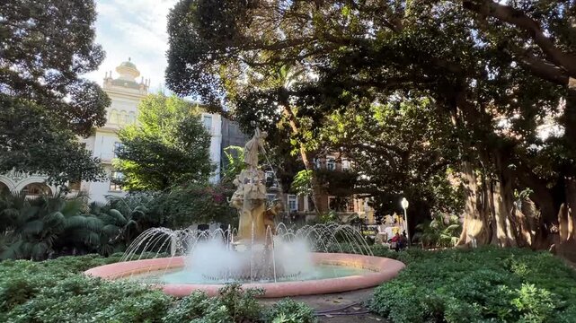 Fountain and big trees at Placa Gabriel Miro in Alicante Spain