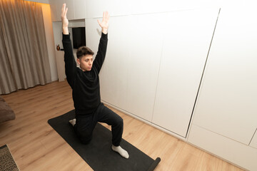 Young man practicing yoga lunge pose at home