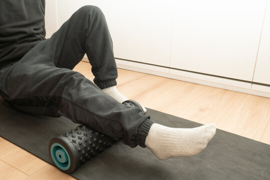 Person rolling leg muscle with foam roller for recovery