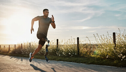 A determined athlete with a prosthetic leg sprints along a paved road, showcasing resilience and athleticism.
