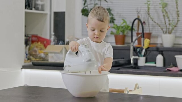 Toddler mixing dough in bowl with electric mixer