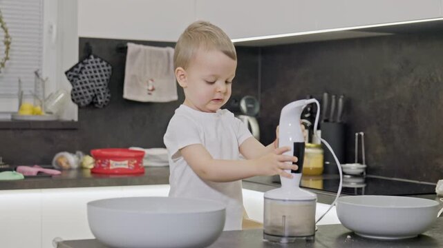 Toddler boy learning to cook with a blender