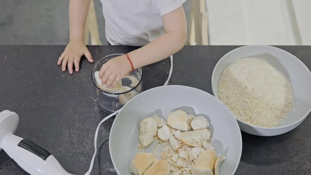 Little child preparing breadcrumbs using a blender
