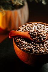 Peeled roasted sunflower seeds in a wooden bowl with a spoon on a dark background