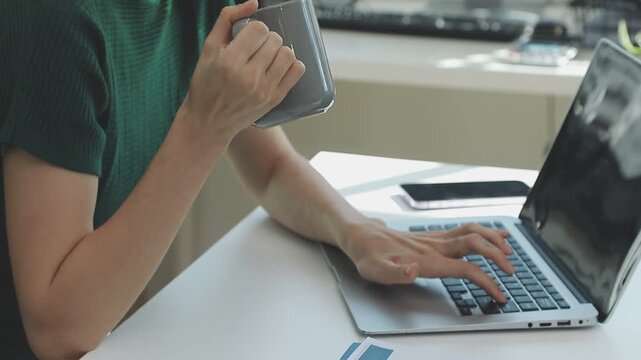 Two financial accountants analysing business spreadsheets on laptop computer, sitting at office desk, looking through paper documents, using calculator working with databases, checking excel tables