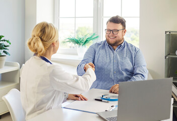 Doctor and patient consultation ends with handshake. A friendly physician gives advice on weight...
