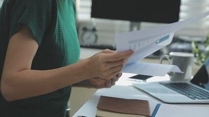 Two financial accountants analysing business spreadsheets on laptop computer, sitting at office desk, looking through paper documents, using calculator working with databases, checking excel tables - Powered by Adobe