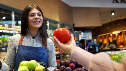 Supermarket employee assisting customer choosing fresh tomatoes - Powered by Adobe