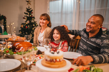 Festive Christmas celebration with family and friends gathered around a joyful holiday feast, wearing Santa hats, enjoying delicious food, desserts, and sparklers in a cozy and decorated home