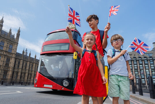Happy tourists kids group posing in front of Big Ben and red bus