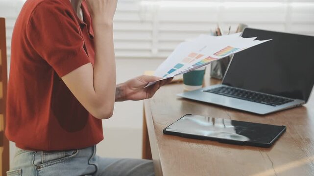 Two financial accountants analysing business spreadsheets on laptop computer, sitting at office desk, looking through paper documents, using calculator working with databases, checking excel tables