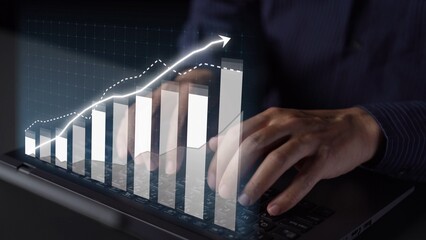 A person typing on a laptop, with a digital graph illustrating growth and trends above, symbolizing business analysis and financial success in a modern workspace. Copula