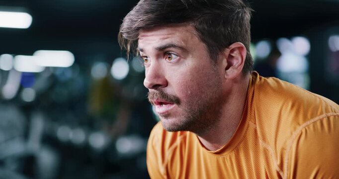 Fitness, fatigue and man in gym with breath control to recover, finish exercise and training exhaustion. Tired, workout endurance and athlete with commitment to health, exhale and bokeh for wellness