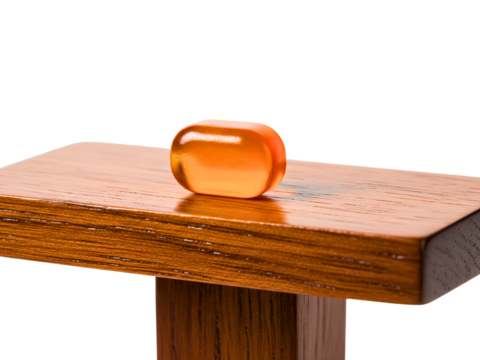 Orange gelatin capsule supplement on brown wooden surface on a transparent background