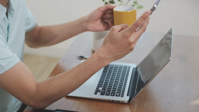 Two financial accountants analysing business spreadsheets on laptop computer, sitting at office desk, looking through paper documents, using calculator working with databases, checking excel tables
