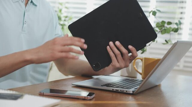 Two financial accountants analysing business spreadsheets on laptop computer, sitting at office desk, looking through paper documents, using calculator working with databases, checking excel tables
