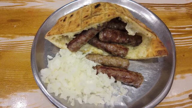 Close-up video of traditional grilled cevapi served in lepinja with chopped onions, showing authentic Bosnian cuisine and delicious street food presentation