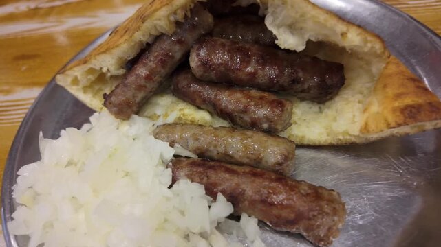 Detailed close-up of cevapi in warm lepinja with fresh onions, highlighting texture, flavor and authentic Balkan street food style