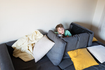 Boy relaxing on sofa with pet dog at home