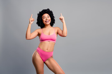 Confident young woman in pink bikini poses with a cheerful smile promoting fitness lifestyle and...