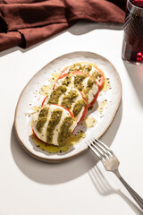 Italian caprese salad with tomatoes and mozarella. Pesto sauce and olive oil.