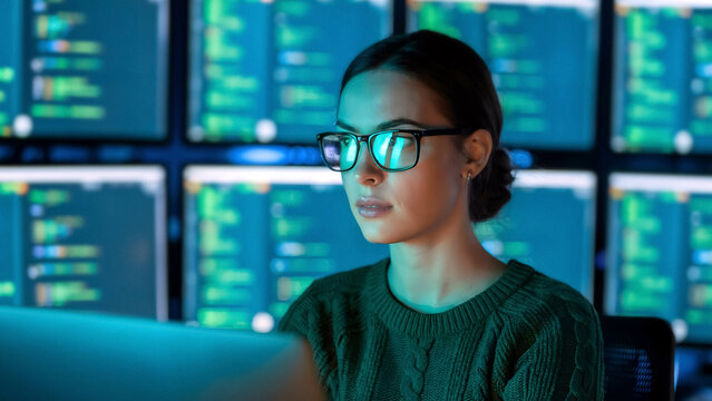 Focused programmer coding with multiple screens in a modern tech startup environment for innovative solutions