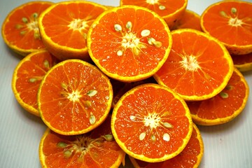 A vibrant, high-angle close-up showcases a rich arrangement of freshly sliced oranges, their vivid, bright orange flesh and textured rinds creating a natural, inviting pattern.