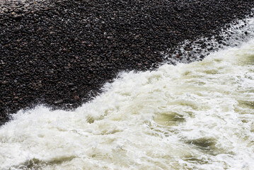Close Up Wave Splashing Against Dark Stone. Shore Landscape