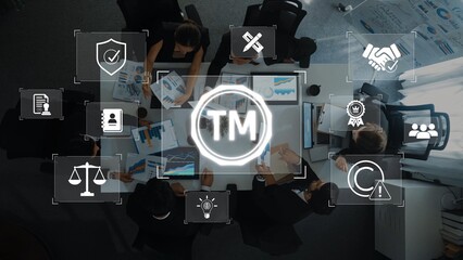A top-down view of business professionals collaborating in a conference room, analyzing visual data and discussing strategies while surrounded by trademark symbols and icons. Raster
