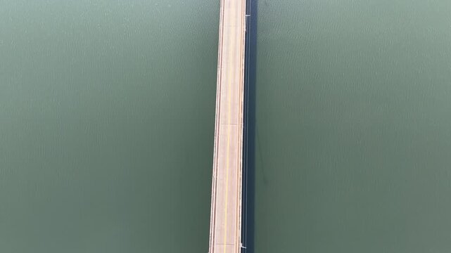 Aerial view of a bridge with cars crossing over a body of water seen