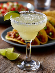 Margarita cocktail with lime and tacos in the background.