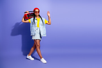 Young woman with retro streetwear poses with a red boombox against a purple background in a vibrant fashion lifestyle shoot