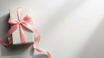 A pristine white gift box, elegantly tied with a charming pink ribbon and bow, rests on a bright surface with subtle lighting, symbolizing heartfelt presents and joyous celebrations