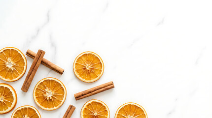 Dried orange slices and cinnamon sticks arranged on a white marble background from a top-down view.