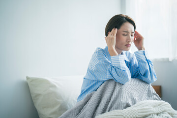 体調不良の女性、彼女は顔を顰めながらこめかみを押さえている