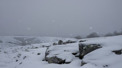 Snowy winter landscape scene with snow-covered rocks and hills creating a peaceful, serene atmosphere perfect for nature or holiday-themed projects